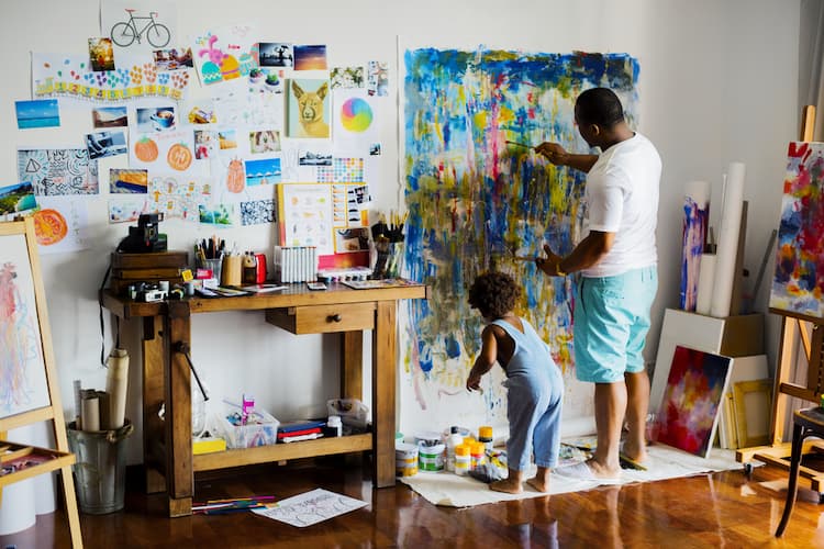 Artist father painting canvas with his young son