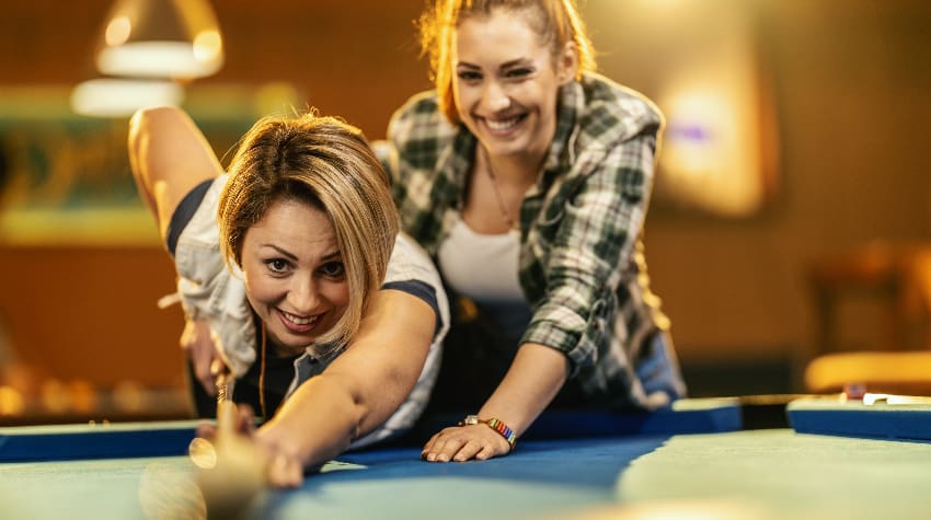 Two woman play billiards in a casual bar