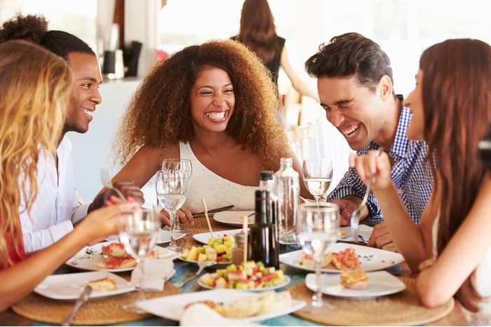 friends gather at a restaurant table and smile