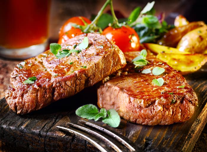 two steaks arranged on a wood platter