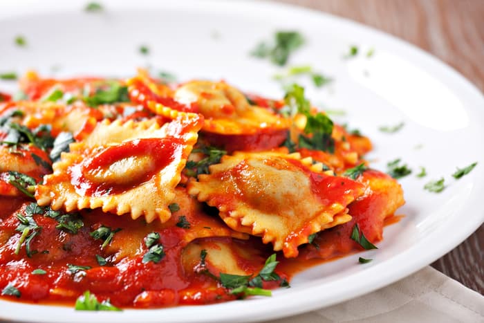 ravioli in a red sauce topped with herbs