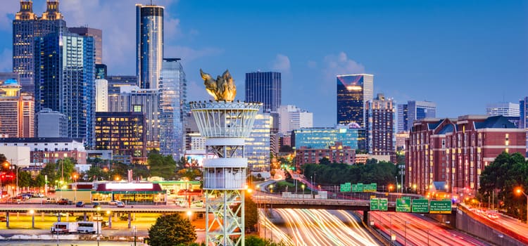 a view of the atlanta skyline at dusk, with the olympic torch sculpture in the forefront