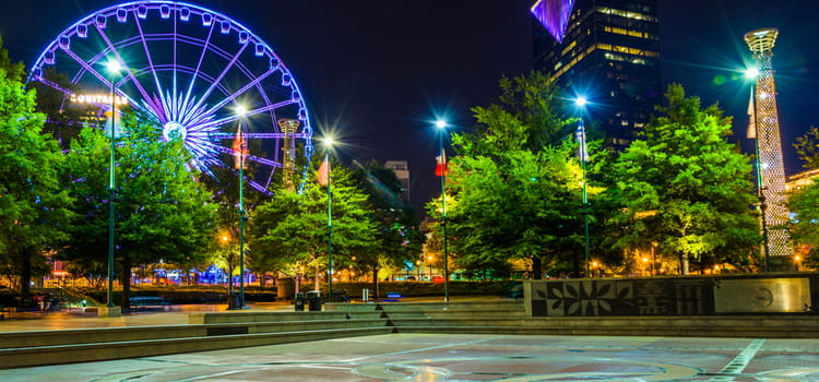 an open fountain area at centennial olympic park after dark, with the lit ferris wheel in the background
