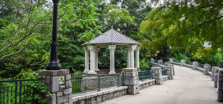 a small gazebo off of a paved trail lined with stone at piedmont park