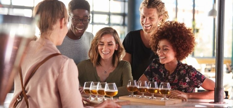 a group of people being served beer flights at a brewery