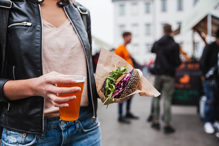 Woman holding a sandwich and drink at a festival